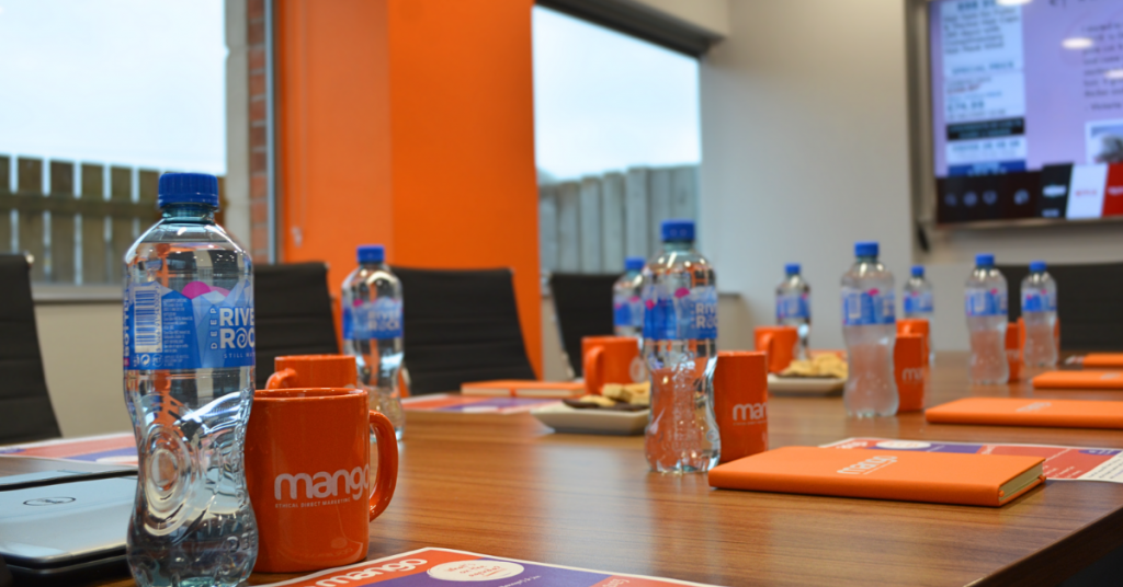 mango direct marketing boardroom, orange mugs and notebooks, bottles of water, contact centre outsourcing meeting